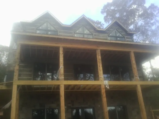 Dormers and porch framing on a large log home under construction — Roof Coating work by our crew in Callaway